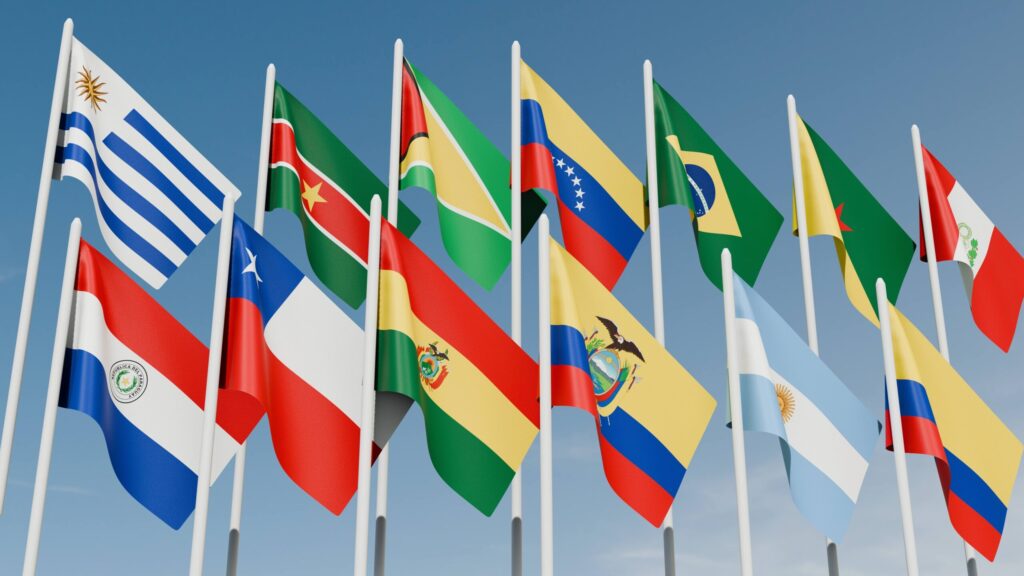 Banderas de países latinoamericanos ondeando al aire, símbolo de unidad sindical y regional, relacionadas con la propuesta en la CEPAL sobre cuidado como derecho humano, empleo e inversión social.