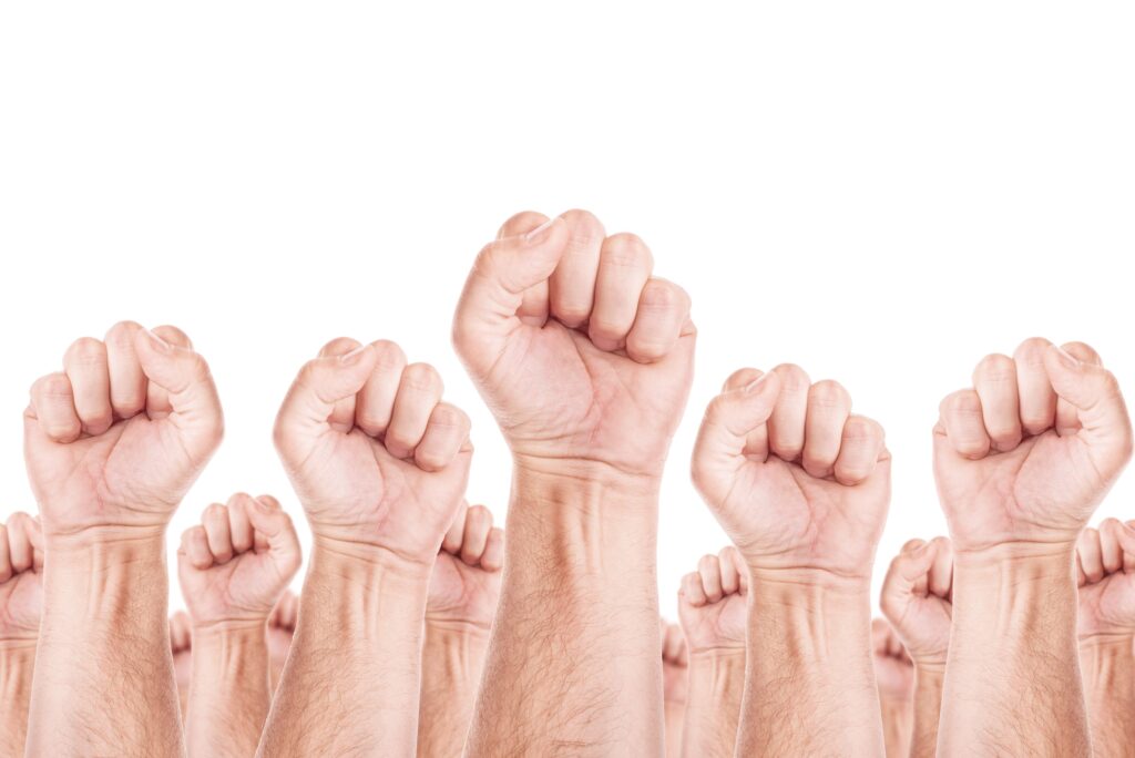 Grupo de personas levantando el puño como símbolo de unidad y resistencia en apoyo a los sindicatos y la protección de derechos laborales.