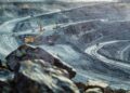 Vista panorámica de una mina a cielo abierto con maquinaria pesada y caminos en espiral, utilizada para extracción de minerales.