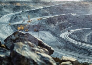 Vista panorámica de una mina a cielo abierto con maquinaria pesada y caminos en espiral, utilizada para extracción de minerales.