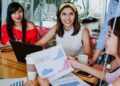 Grupo de mujeres en una reunión revisando gráficos y estadísticas impresas, reflejando la participación femenina en espacios de liderazgo y toma de decisiones laborales.