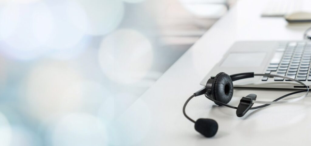 Audífonos de call center sobre escritorio con laptop, representando trabajo en México bajo revisión del T-MEC por derechos laborales.