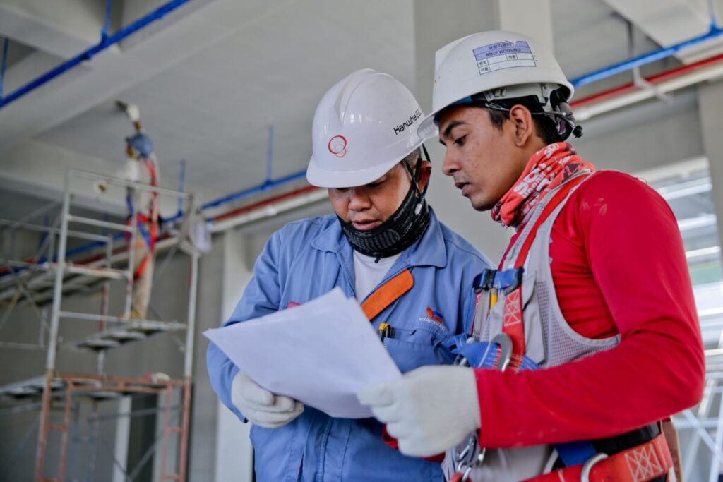 Obreros con casco y equipo de seguridad en obra, simbolizando seguridad laboral y muertes en construcción.