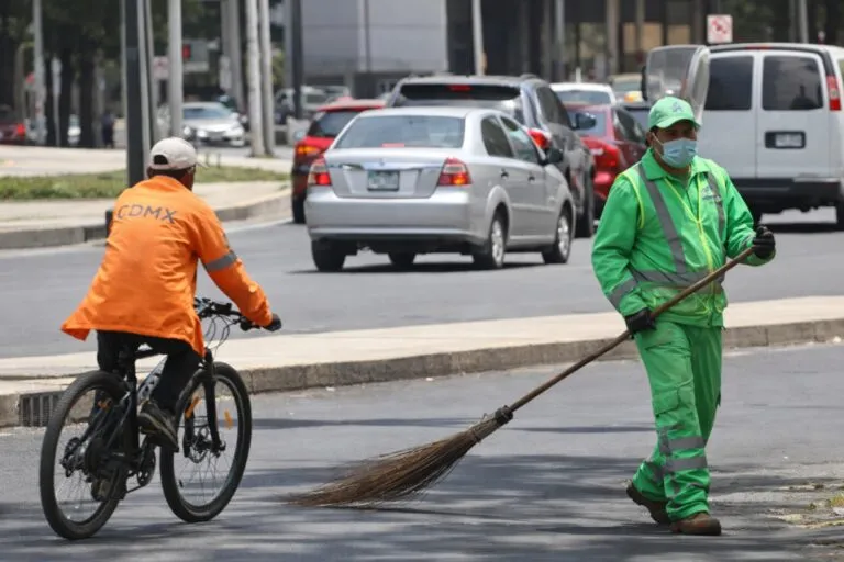 Trabajador de limpieza en uniforme verde barriendo calles de la Ciudad de México