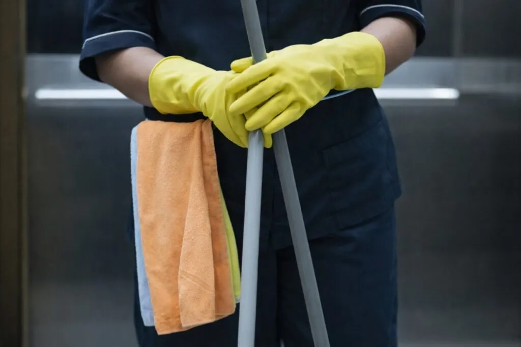 Mujer migrante con guantes de limpieza representa la explotación laboral en sectores domésticos en España