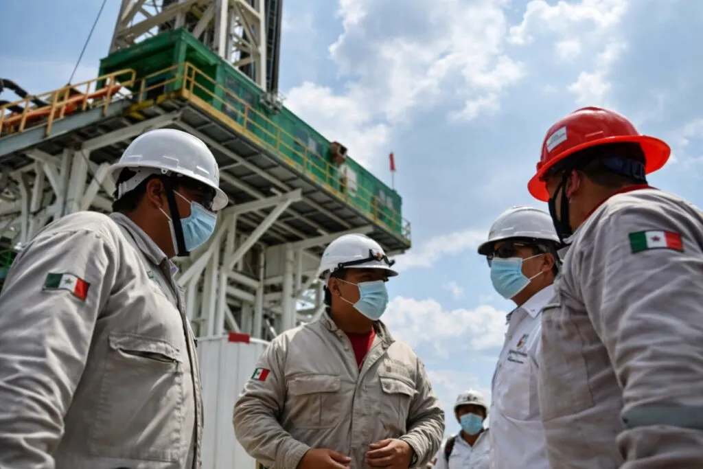 Trabajadores de Pemex dialogan con equipo de protección en una planta de extracción de petróleo en México