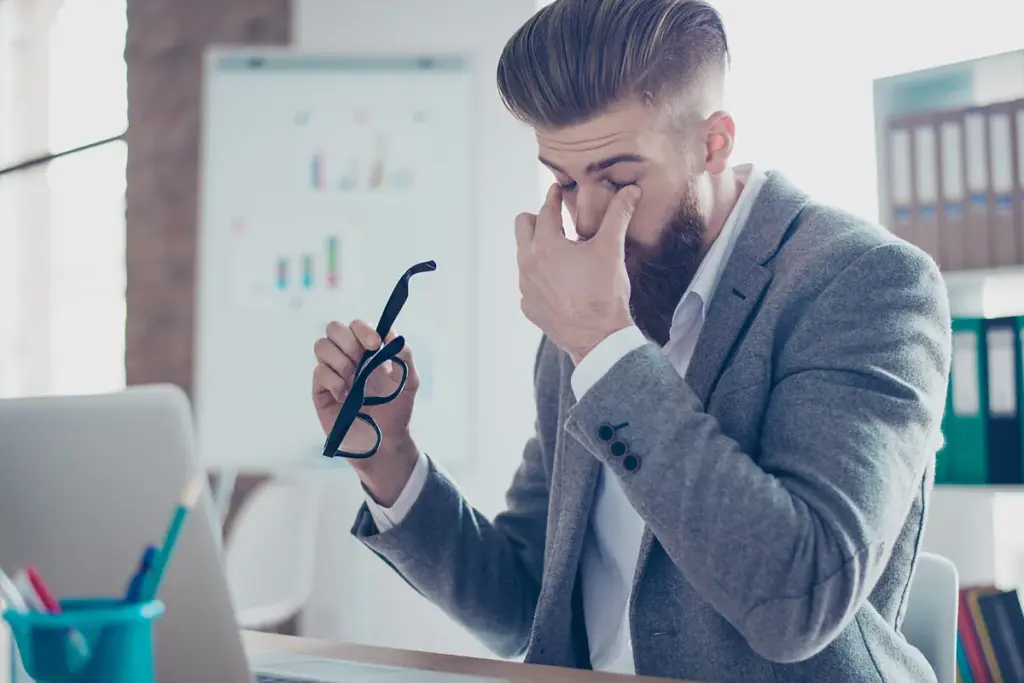 Trabajador reflexivo en oficina moderna que representa la crisis de los hombres en el trabajo y los cambios del mercado laboral global