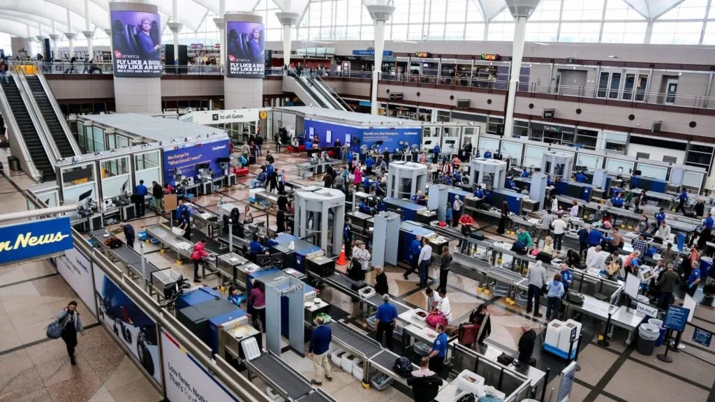 Aeropuerto en Estados Unidos con personal de seguridad y pasajeros en revisión, reflejando el conflicto laboral denunciado por sindicatos de sobrecargos y la falta de agentes de la TSA