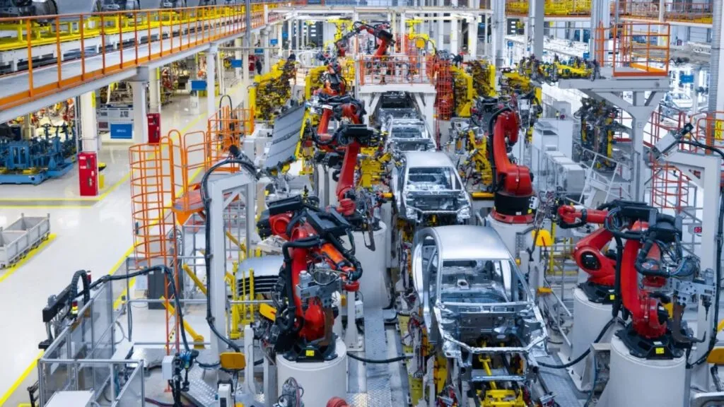 industria automotriz global con trabajadores en planta y producción de vehículos mostrando diferencias laborales entre países
