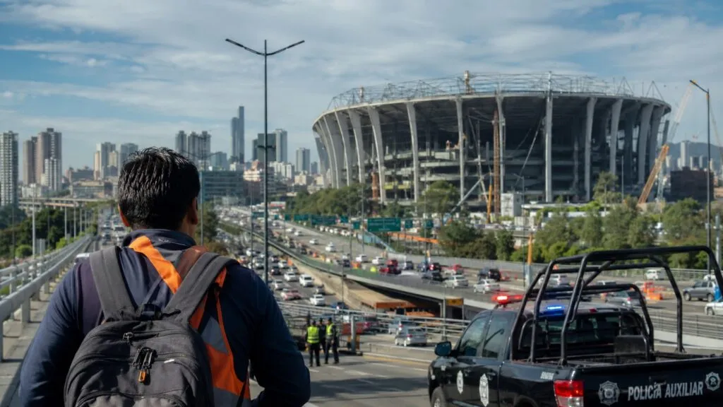 Trabajador observando obras de infraestructura y operativos de seguridad alrededor de un estadio sede del Mundial 2026 en México.