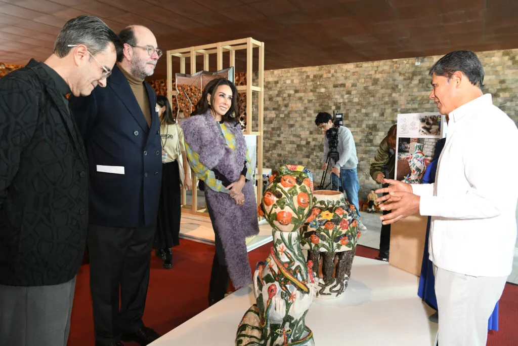 Creador presenta piezas de cerámica decorada ante visitantes de Design Week México 2026 durante una exposición de artesanía.